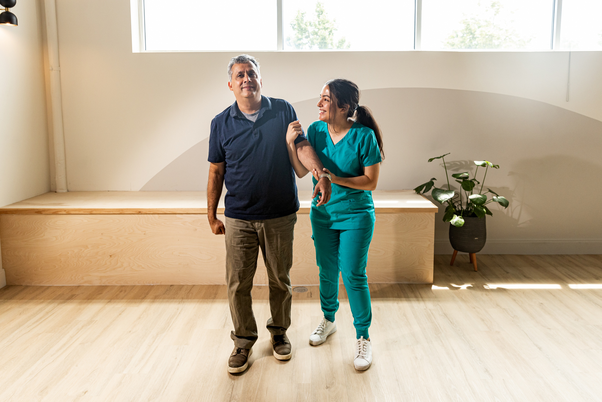 Nurse helping elderly man with rehabilitative physiotherapy